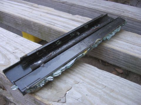 1995 Ford Bronco - A damaged window channel with broken glass pieces rests on weathered wooden planks.