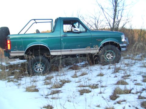1996 Ford Bronco - A modified 1996 Ford Bronco sits in a snowy, grassy field with trees in the background.