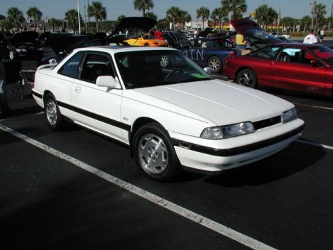 1996 Ford Probe - A white coupe with a GT badge is parked at an outdoor event with other cars.