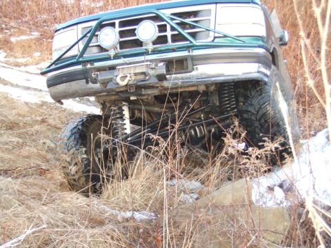 1996 Ford Bronco - This modified Ford Bronco is shown from the front, angled upwards on a grassy, snowy incline.