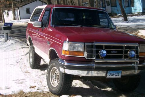 1993 Ford Bronco - A red 1993 Ford Bronco is parked on a street with snow on the ground.