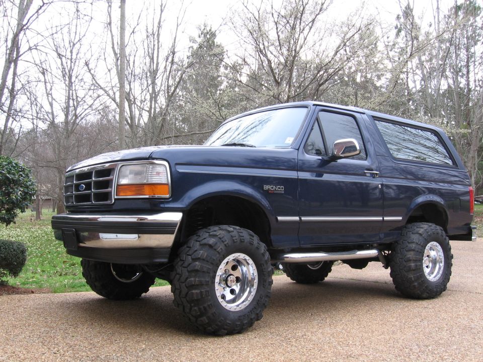 Dark blue Ford Bronco with lifted suspension and large off-road tires, parked outdoors