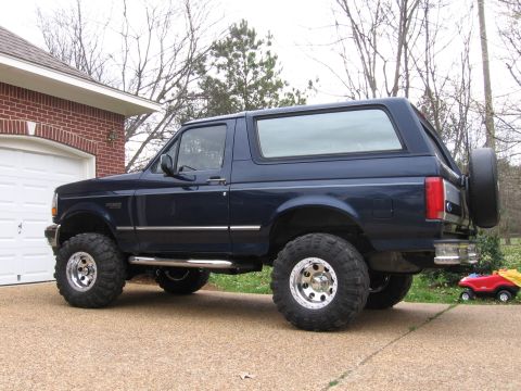 1967 Ford Mustang - This Ford Bronco is parked in front of a brick garage with a white door.