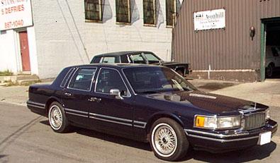 1996 Ford F-150 - A dark blue sedan is parked on the street in front of a building with a garage.