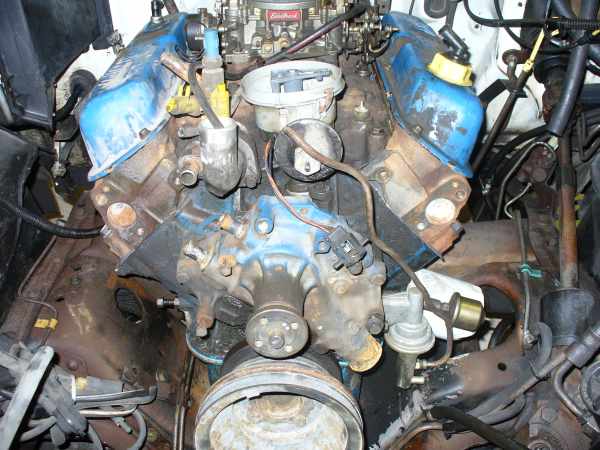 V8 engine with blue valve covers and Edelbrock carb in engine bay, front accessories removed