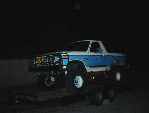 1981 Ford Bronco - Ford Bronco loaded onto a trailer at night, showing its 3/4 front view.