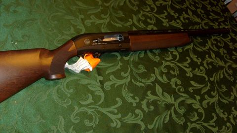 1995 Ford C-350 (Centurion Conversions) - Beretta shotgun with wooden stock and orange tag visible on a patterned green cloth.
