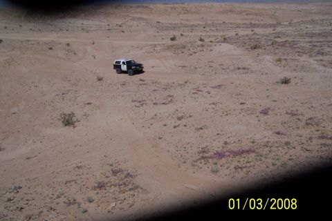 1990 Ford Bronco - A 1990 Ford Bronco navigates a desert landscape, its black and white exterior contrasting with the sandy terrain.