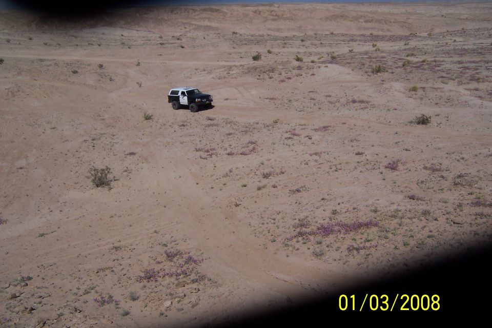 1990 Ford Bronco in desert, 3q-front view, black and white with camper shell