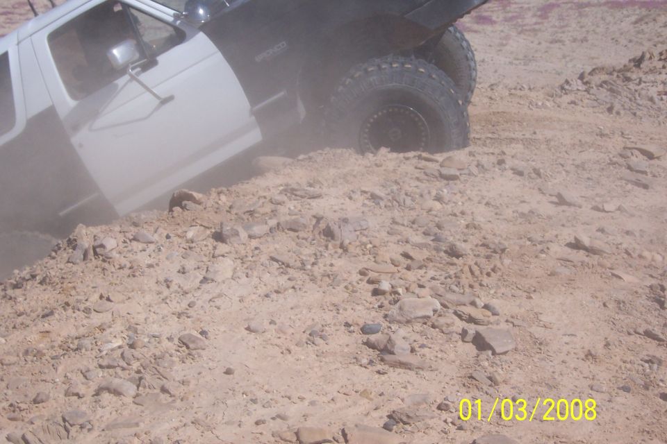 White 1990 Ford Bronco climbing rocky terrain