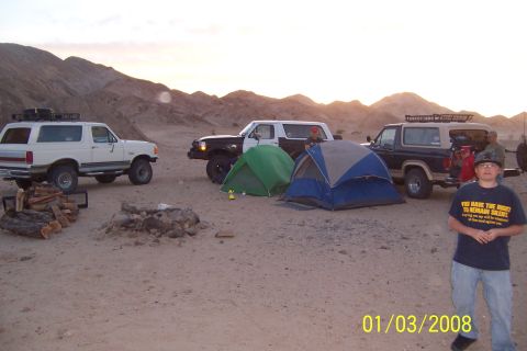 1990 Ford Bronco - Camping trip with three Ford Broncos in the desert, tents and a campfire scene.