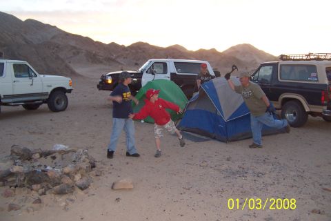 1990 Ford Bronco - People are setting up camp in a desert landscape with several Ford Broncos nearby.
