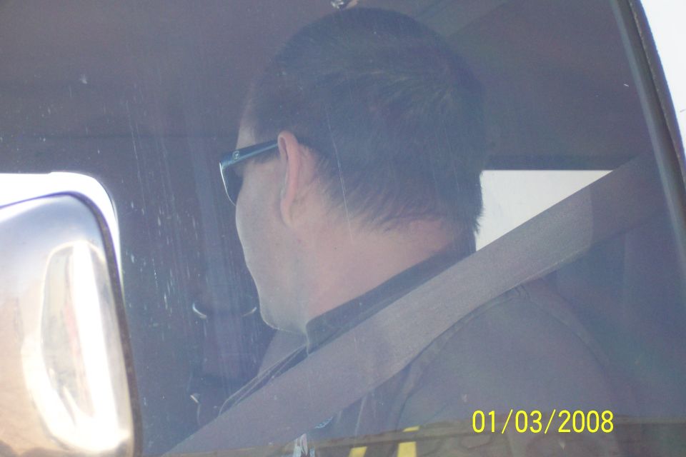 Driver wearing sunglasses inside a vehicle, seatbelt fastened