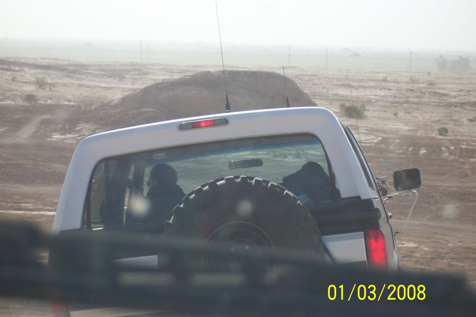 1990 Ford Bronco rear view, spare tire on door, in a dusty, outdoor landscape