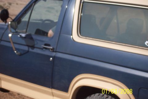 1990 Ford Bronco - This Ford Bronco features a two-tone blue and tan paint scheme with a prominent side trim.