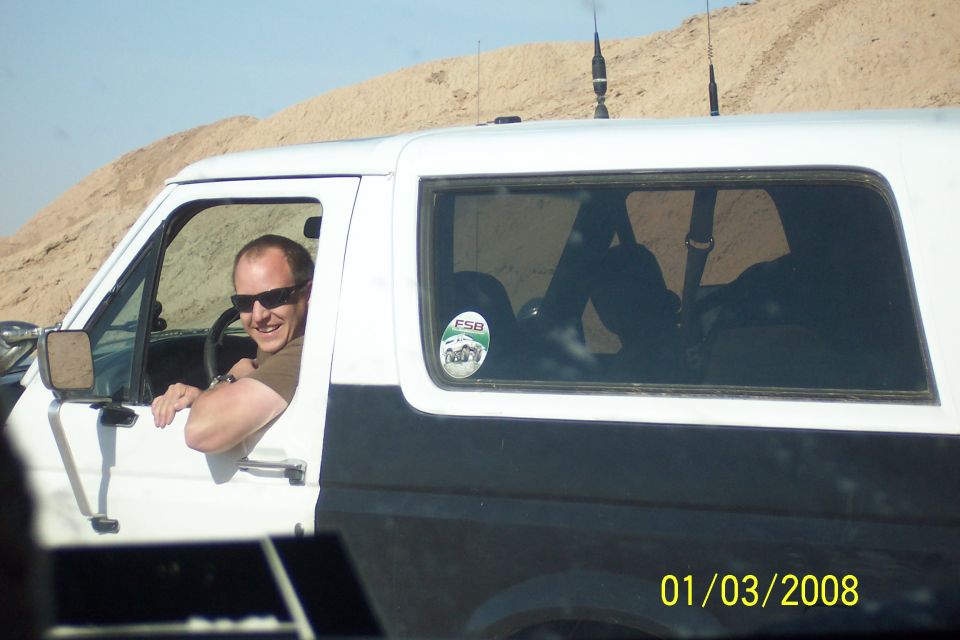 White and black Ford Bronco with a man driving, side view