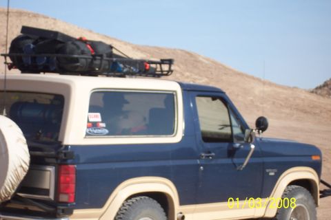 1990 Ford Bronco - This blue and tan 1990 Ford Bronco is equipped with a roof rack carrying camping gear and a spare tire mounted on the rear.