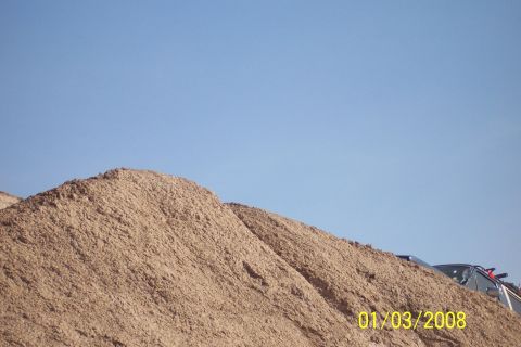 1990 Ford Bronco - A pile of dirt with vehicles partially visible on top under a clear blue sky.