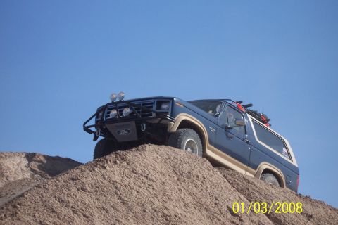 1990 Ford Bronco - This Ford Bronco is climbing a steep dirt incline under a clear blue sky.