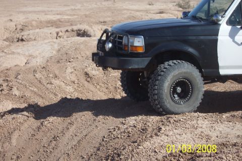 1990 Ford Bronco - This Ford F-Series truck is equipped with large off-road tires and a brush guard, seen in a desert landscape.