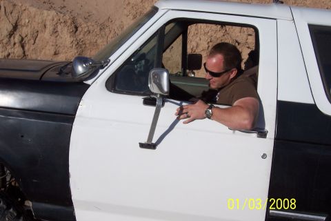 1990 Ford Bronco - Man leans out the driver's door of a 1990 Ford Bronco. The vehicle has a two-tone paint scheme.