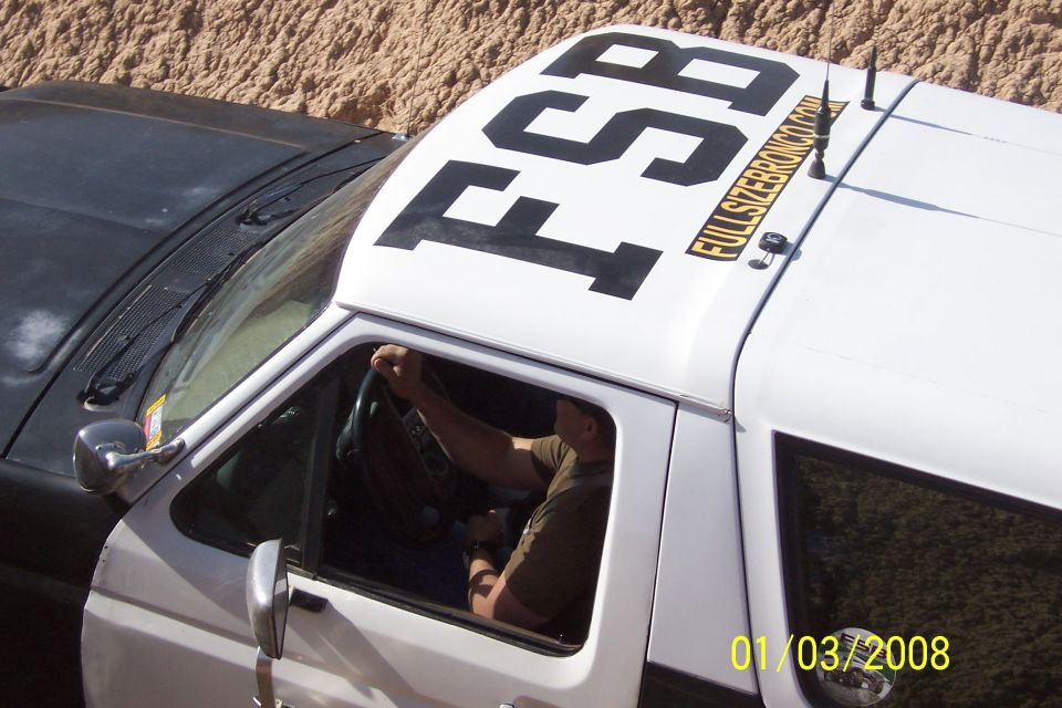 White Ford Bronco with black lettering 'FSB' on the roof and 'FULLSIZERBRONCO.COM' text