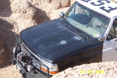 1990 Ford Bronco - A Ford Bronco is partially submerged in a sandy ditch, its front end equipped with a winch and brush guard.