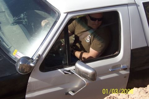 1990 Ford Bronco - A man is inside the cab of a white truck, looking down and to the right.