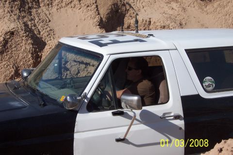 1990 Ford Bronco - A 1990 Ford Bronco, painted black and white, is driven off-road with large numbers visible on its roof.
