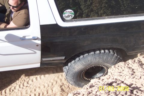1990 Ford Bronco - This Ford Bronco appears to be stuck in the dirt while off-roading, with a driver visible inside.