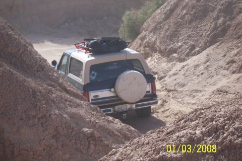 1990 Ford Bronco - This 1990 Ford Bronco navigates a narrow, sandy path between steep, eroded canyon walls.