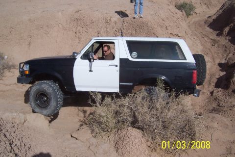1990 Ford Bronco - This Ford Bronco is navigating a challenging off-road terrain with steep inclines and loose dirt.