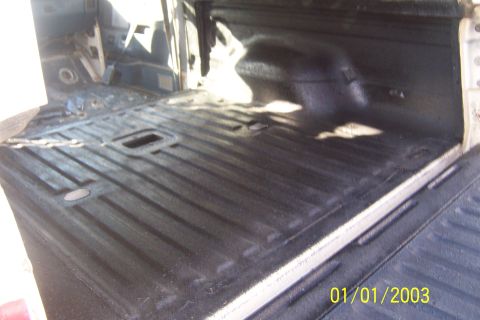 1990 Ford Bronco - The interior of a pickup truck bed has been sprayed with a black bedliner. The ribbed floor and wheel wells are visible, along with a date…
