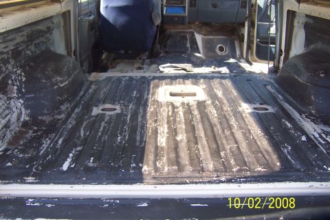 1990 Ford Bronco - The interior of a pickup truck bed is shown, with the cab and seats visible in the background. The bed appears to be stripped down and unde…