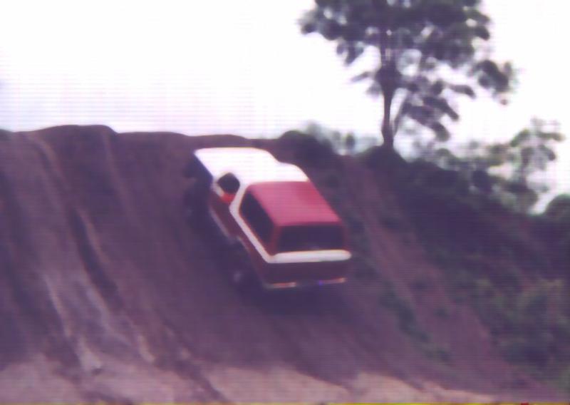 Red and white SUV climbing a steep dirt embankment, blurry photo