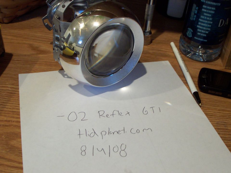 Car headlight projector assembly on a table with handwritten notes.