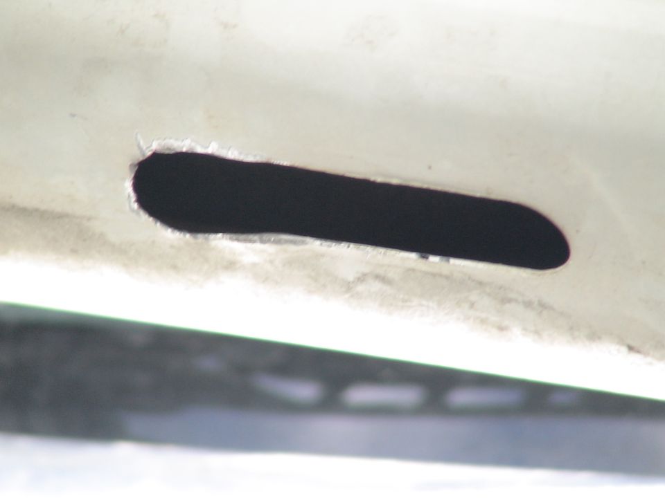 Close-up of a black slot cut into a white vehicle panel.