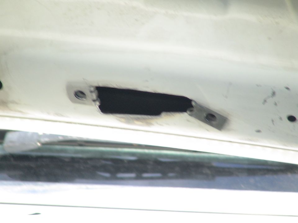 Close-up of a cutout with metal brackets on the white underside of a vehicle.
