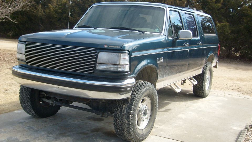 Teal Ford-based Centurion conversion 4-door SUV, lifted, front 3/4 view on driveway