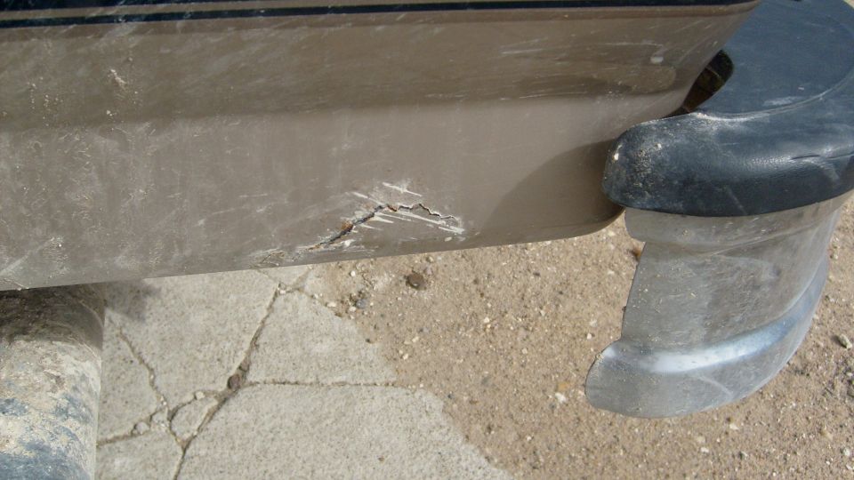 Close-up of a cracked tan plastic running board step with black end cap on a vehicle