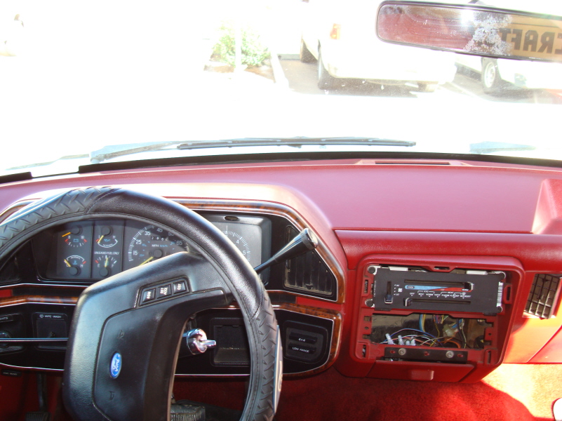 Interior of a red 1989 Ford Bronco dashboard with steering wheel, instrument cluster, and car stereo.