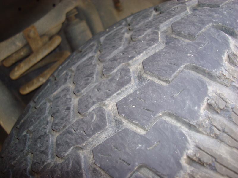 Close-up of worn tire tread and damaged sidewall.