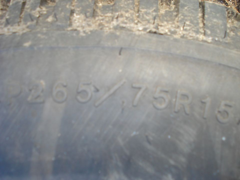 Close-up of a P265/75R15 tire sidewall with dirt on the tread.