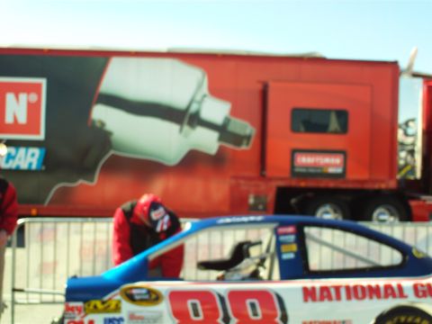 1978 Ford Bronco - A race car with the number 98 and the text "NATIONAL GU" is visible in the foreground, with a large red truck in the background. A person i…