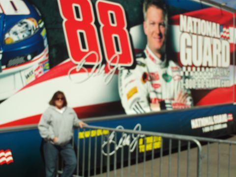 1978 Ford Bronco - A woman stands in front of a large mural featuring a race car driver and the number 88. The mural also has "National Guard" branding.