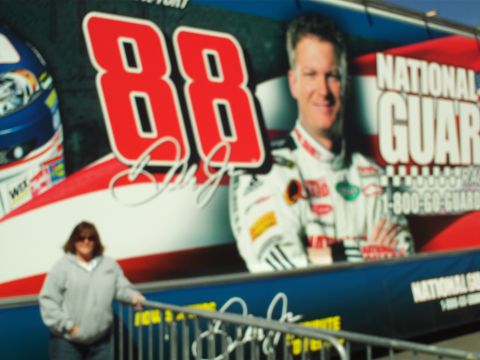 1978 Ford Bronco - A woman stands in front of a large banner featuring a race car driver and the number 88. The banner also displays "NATIONAL GUARD" and spon…