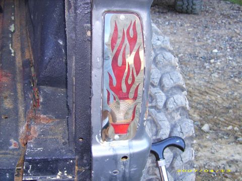 1978 Ford Bronco - Custom taillight with flame design on a vehicle's rear, next to a large off-road tire.