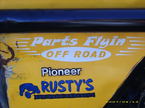 1978 Ford Bronco - Decals on the side of a yellow vehicle read 'Parts Flyin Off Road' and 'Pioneer Rusty's Off-Road Products'.