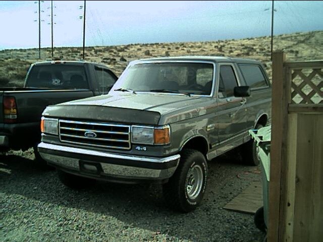 Gray two-tone Ford Bronco 4x4 SUV parked on gravel, front driver-side three-quarter view