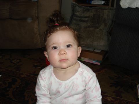 2000 Ford Crown Victoria - A young child with a topknot hairstyle looks directly at the camera while sitting indoors.